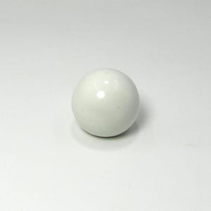 Op de afbeelding: Een effen, crèmekleurige bol, waarschijnlijk van keramiek of porselein, met een glanzende afwerking. De bal is glad en rond, en reflecteert licht. Het object staat op een witte ondergrond, wat duidt op een decoratief of functioneel item.