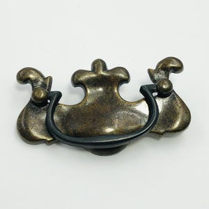 May include: A white ceramic mug with a black handle and the text "But First, Coffee" in a black, handwritten-style font. The mug is on a white surface.