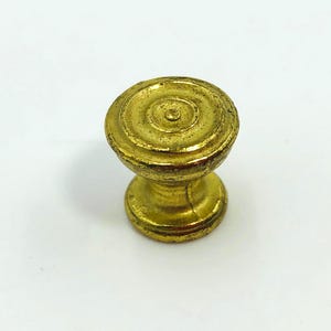 May include: A gold-colored cabinet knob with a spiral design on the top. The knob has a rounded shape with a short, cylindrical base. The finish appears aged, giving it a vintage look. Ideal for furniture restoration or adding a touch of elegance.