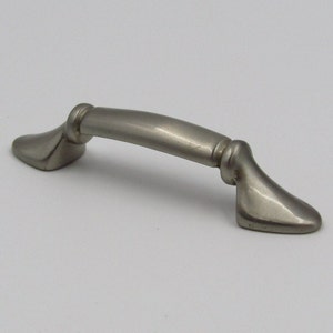 May include: A silver cabinet pull with a curved design and rounded ends. The pull has a brushed finish.