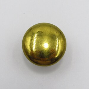 Puede incluir: Un bot&oacute;n redondo de color dorado con una superficie lisa y brillante.