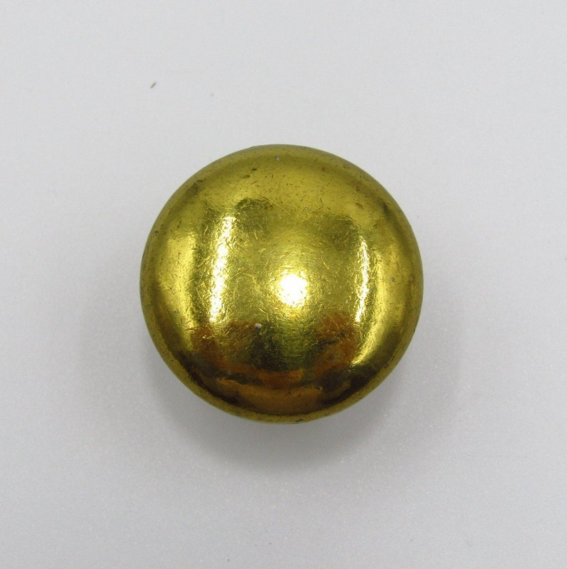 Puede incluir: Un bot&oacute;n redondo de color dorado con una superficie lisa y brillante.