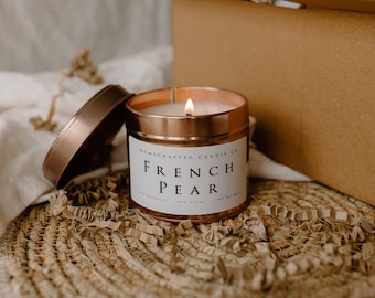 May include: A copper candle jar with a white label that reads "Homecrafted Candle Co. French Pear". The candle is lit and the jar is sitting on a woven mat.