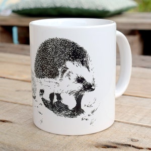 Peut inclure: Une tasse en céramique blanche avec une illustration en noir et blanc d'un hérisson. Le hérisson est tourné vers la droite de la tasse et a une illustration détaillée de ses piquants.