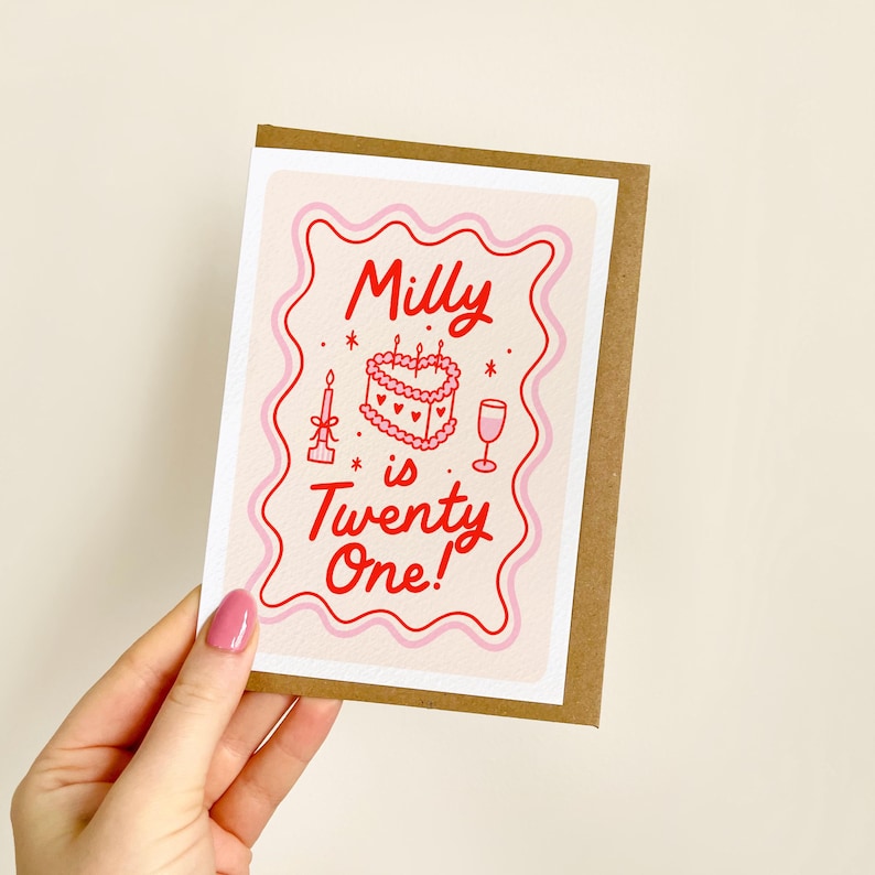 Puede incluir: Tarjeta de cumplea&ntilde;os con borde marr&oacute;n y dise&ntilde;o rosa y blanco. La tarjeta dice "Milly is Twenty One!" en escritura roja. El dise&ntilde;o incluye un pastel, una vela y una copa de vino.