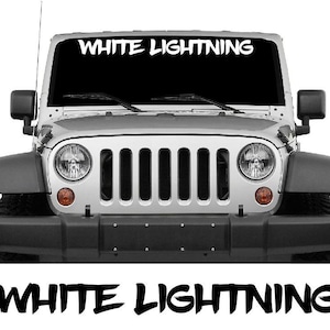 May include: A silver Jeep Wrangler with the text "WHITE LIGHTNING" across the top of the windshield. The text is also displayed in a larger font at the bottom of the image. The vehicle has a black front bumper and black fender flares.