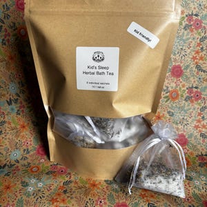 May include: A brown kraft paper pouch containing herbal bath tea with a label reading Honey's Kid's Sleep Herbal Bath Tea, 8 individual satchels, 14.1 net oz, and a Kid friendly! sticker, accompanied by a single white organza sachet of bath tea.