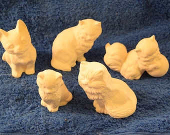 May include: A set of six ceramic cat figurines in various poses. The figurines are all white and have a smooth, matte finish.