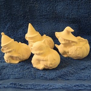 May include: Four ceramic Halloween figurines of cats dressed as witches and goblins, each holding a pumpkin. The figurines are white and unpainted.