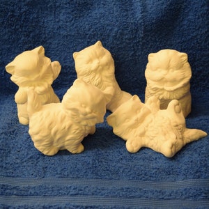 May include: Five white ceramic cat figurines in various poses. The cats are all in a playful or relaxed position.