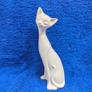 May include: White ceramic cat figurine with a sleek, stylized design. The cat is sitting with its tail curled around its body and has a closed-eye expression.