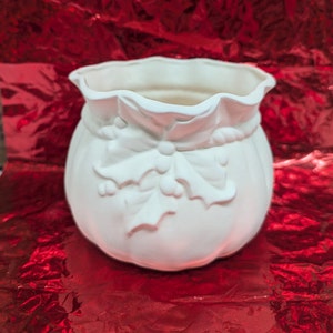 May include: White ceramic Christmas-themed planter shaped like a sack with a holly and bow design.