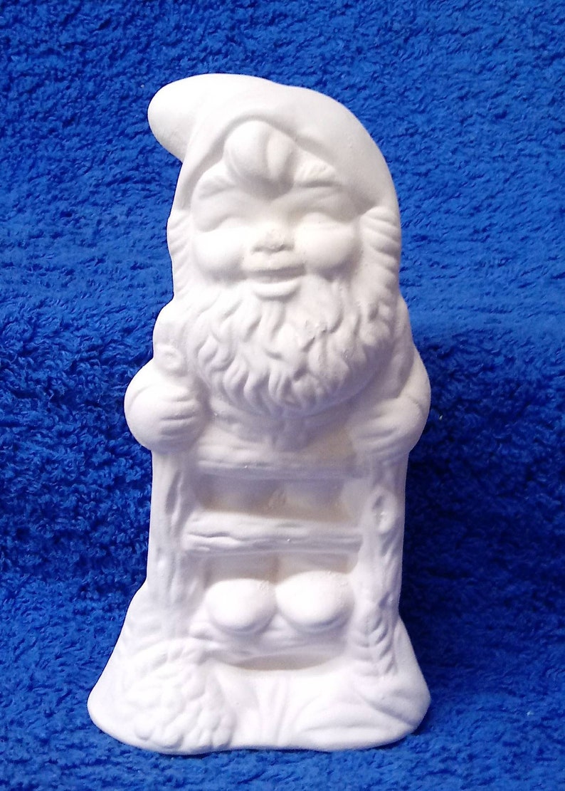 May include: White ceramic gnome figurine with a smiling face and a beard. The gnome is sitting on a ladder with his hands on the rungs.