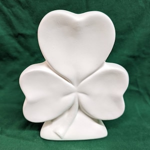 May include: White ceramic shamrock shaped ornament. The shamrock has three leaves and a stem.