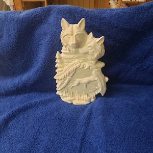 K&ouml;nnte beinhalten: Wei&szlig;e Keramikskulptur von zwei W&ouml;lfen mit einem Wolfswelpen, der vor ihnen l&auml;uft. Die W&ouml;lfe befinden sich in einer Waldkulisse mit B&auml;umen und Bl&auml;ttern.