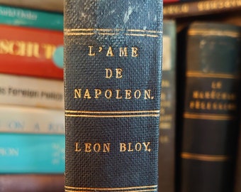 May include: A vintage hardback book with a dark blue cover and gold lettering. The title is "L'AME DE NAPOLEON." The author is "LEON BLOY."