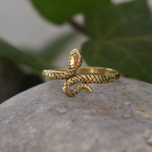 May include: A gold snake ring with a detailed snake design. The snake is curled around the band of the ring.
