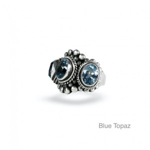 May include: A silver ring with three blue topaz gemstones set in a decorative design.