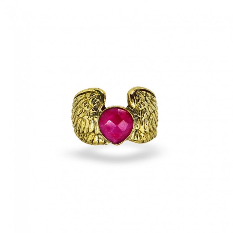 Puede incluir: Anillo de oro con una piedra preciosa rosa en forma de coraz&oacute;n y alas de &aacute;ngel a cada lado.