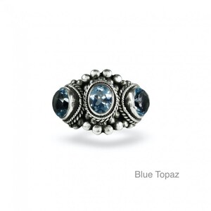 May include: A silver ring with three blue topaz gemstones set in a decorative design.