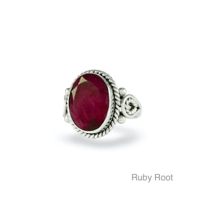 May include: A sterling silver ring featuring an oval, deep red ruby gemstone. The ruby is set within a rope-textured bezel, with decorative silver accents on the sides. The ring is displayed on a white background, with the text "Ruby Root" at the bottom.