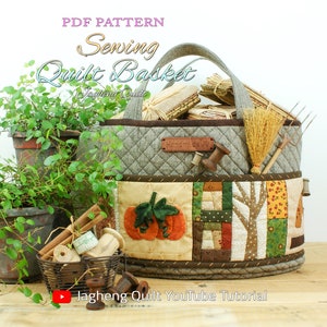 May include: A grey quilted fabric basket with a brown handle and a patchwork design featuring pumpkins, trees, and other autumn motifs. The basket is filled with various items, including a broom, a rake, and a spool of thread. The text "PDF PATTERN Sewing Quilt Basket" is displayed at the top of the image.