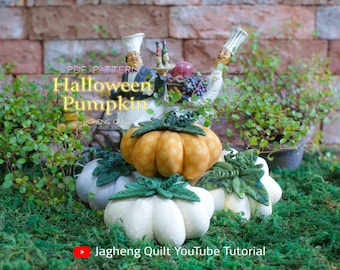 Peut inclure: Plusieurs citrouilles en tissu faites à la main, de couleurs orange et blanche, avec des feuilles vertes. Elles sont disposées sur de la mousse verte. Le texte "Halloween Pumpkin" est visible.