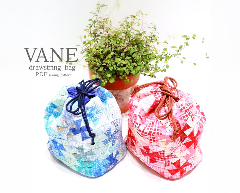 K&ouml;nnte beinhalten: Zwei Patchwork-Kordelzugbeutel, einer blau und einer rot, mit dem Text "VANE drawstring bag PDF sewing pattern". Die Beutel bestehen aus kleinen, geometrischen Stoffst&uuml;cken und haben Kordelverschl&uuml;sse. Eine kleine Topfpflanze befindet sich im Hintergrund.