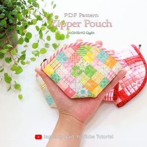 May include: A pink and red zipper pouch with a patchwork design. The pouch is made of fabric squares in various colors and patterns. The pouch is being held in a hand. The text "PDF Pattern Zipper Pouch" and "JagHeng Quilt" is visible at the top of the image. The text "JagHeng Quilt YouTube Tutorial" is visible at the bottom of the image.
