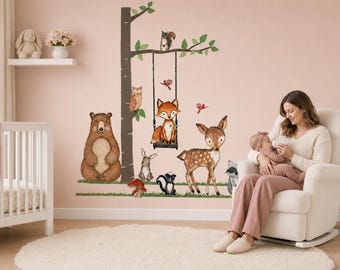 May include: A wall decal set featuring a large brown bear, a fox sitting on a swing hanging from a tree, a deer, a rabbit, a skunk, a raccoon, an owl, and a mushroom. The illustrations are rendered in a soft, watercolor style with earthy tones.