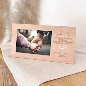 Könnte beinhalten: Ein hellfarbiger Holzbilderrahmen mit einem Foto von zwei Händen, die sich halten. Der Rahmen hat den Text "Liebe Lilly" und weiteren deutschen Text. Das Datum "10.04.2026" ist ebenfalls sichtbar.