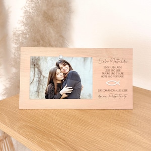 Könnte beinhalten: Ein hellfarbiger Holzbilderrahmen mit einem Foto einer Frau und eines Mädchens. Der Rahmen hat Text auf Deutsch, darunter "Liebe Mathilda" und andere Sätze. Oben am Rahmen befindet sich ein kleiner silberner Kreis.