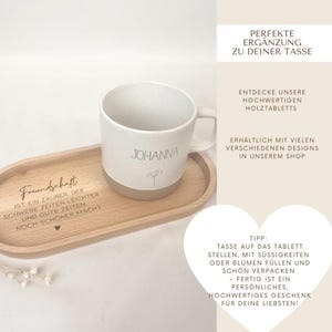 May include: A white ceramic mug with the name "Johanna" and a small floral design, resting on a wooden serving tray. The tray has the word "Freundschaft" and other text. The mug and tray set is a perfect gift.