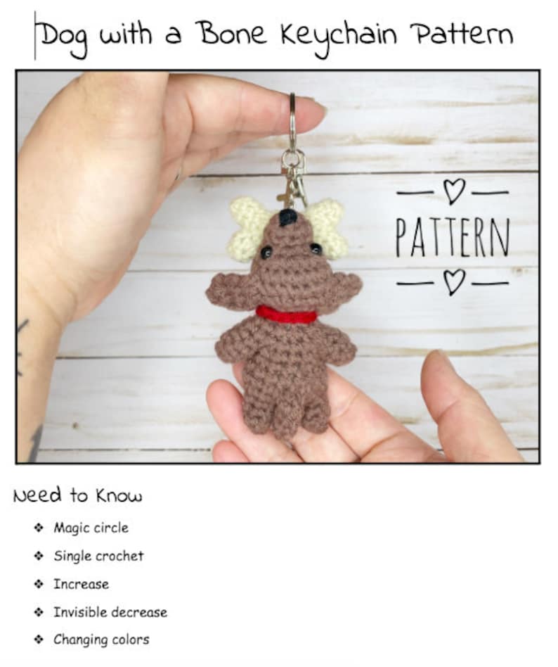 May include: A crocheted dog keychain with bone-shaped accents and a red collar. The keychain is held in front of a light-colored wooden background. The text "Dog with a Bone Keychain Pattern" and "PATTERN" are visible.