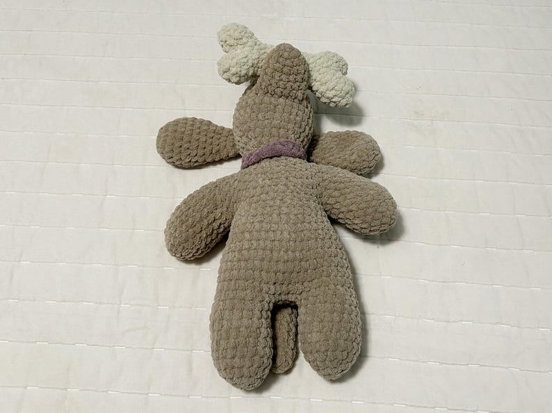 May include: A brown crocheted reindeer plush toy with white antlers and a purple ribbon around its neck.