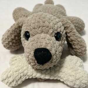 May include: A plush grey and white dog toy with a bone in its mouth. The dog has black eyes and a black nose.
