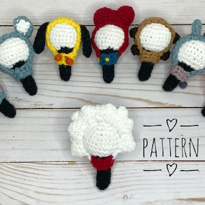 May include: A collection of eight crocheted light-up character toys. Each toy has a different color and design, including a red, a yellow, a brown, a pink, a blue, and a gray. The toys are arranged in a circle around a white crocheted light-up toy with a red base. The text "PATTERN" is written in black below the toys.