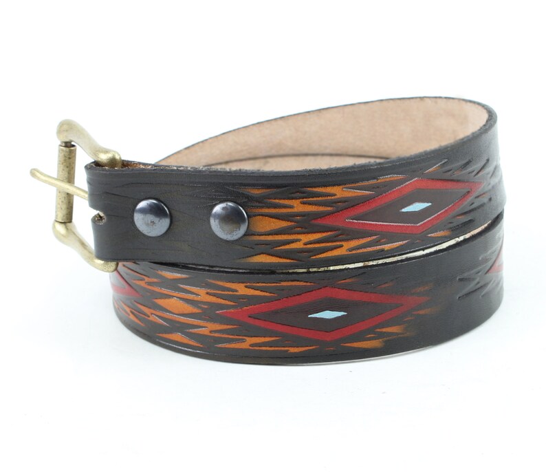 May include: A brown leather belt with a geometric pattern in orange, red, and blue. The belt has a brass buckle and two metal rivets.