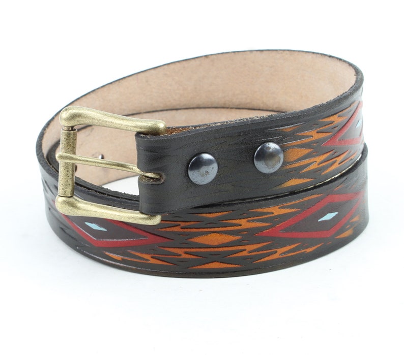 May include: A brown leather belt with a geometric pattern in orange, red, and blue. The belt has a brass buckle and is decorated with silver rivets.