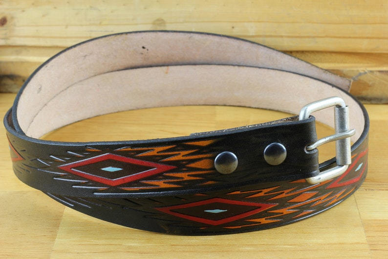 May include: A black leather belt with a geometric pattern in red, orange, and blue. The belt has a silver buckle and two silver rivets.