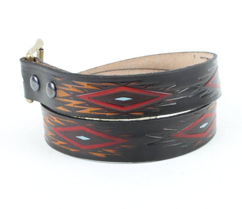 May include: A black leather belt with a geometric pattern in red, orange, and blue. The belt has a silver buckle.