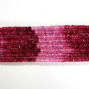 May include: A strand of pink and red gemstone beads. The beads are faceted and have a slightly irregular shape. The beads are strung on a clear thread.