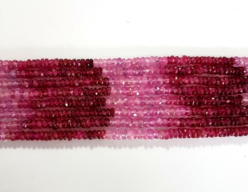 May include: A strand of pink and red faceted gemstone beads. The beads are small and have a slightly irregular shape. The strand is approximately 16 inches long.
