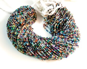 May include: A strand of multi-colored gemstone beads, including blue, green, red, and purple, in a variety of shapes and sizes. The beads are strung on a clear thread and are arranged in a circular pattern.