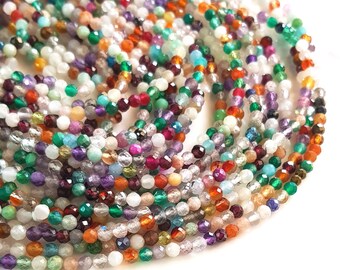May include: A strand of colorful gemstone beads, featuring a variety of colors and shapes, including green, blue, red, purple, and white. The beads are strung on a clear thread and are ready for jewelry making.