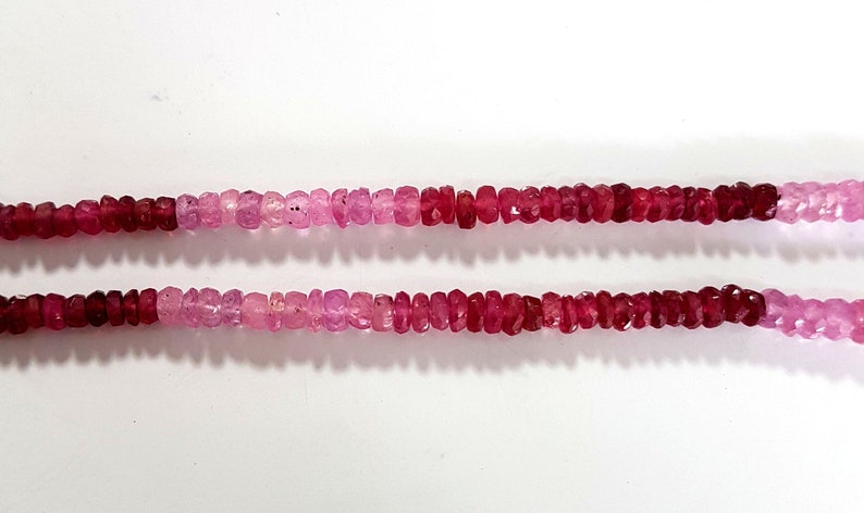 May include: Two strands of pink and red gemstone beads. The beads are faceted and have a graduated color from pink to red.