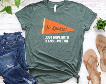 Puede incluir: Una camiseta verde con un gráfico de banderín blanco y naranja que dice "Go Sports! I just hope both teams have fun".