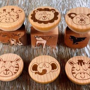 Puede incluir: Seis sellos de animales de madera con caras detalladas. Los sellos incluyen una jirafa, un león, un oso, un tigre, un elefante y una cebra. Cada sello tiene una imagen de animal tallada en la base. Hechos de madera clara.