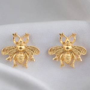 May include: A pair of gold bee stud earrings. The bees are detailed with wings and legs.