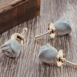 Puede incluir: Tres tiradores de cajón de cerámica en forma de rosa con un esmalte azul claro y herrajes dorados.